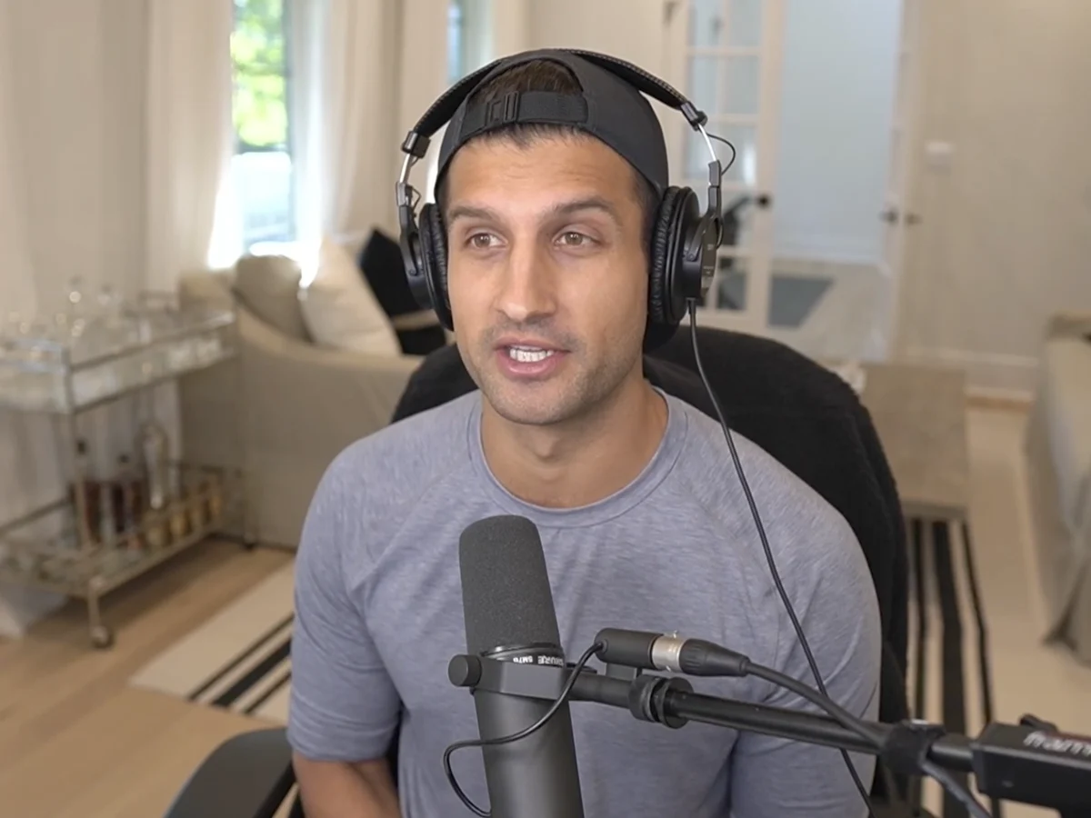 A podcaster in headphones talks into a microphone in his living room