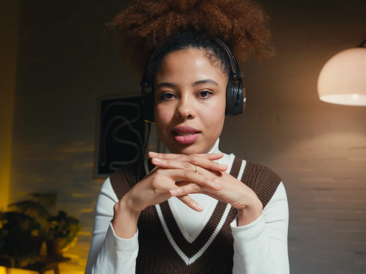 A creator in headphones recording in a warm room