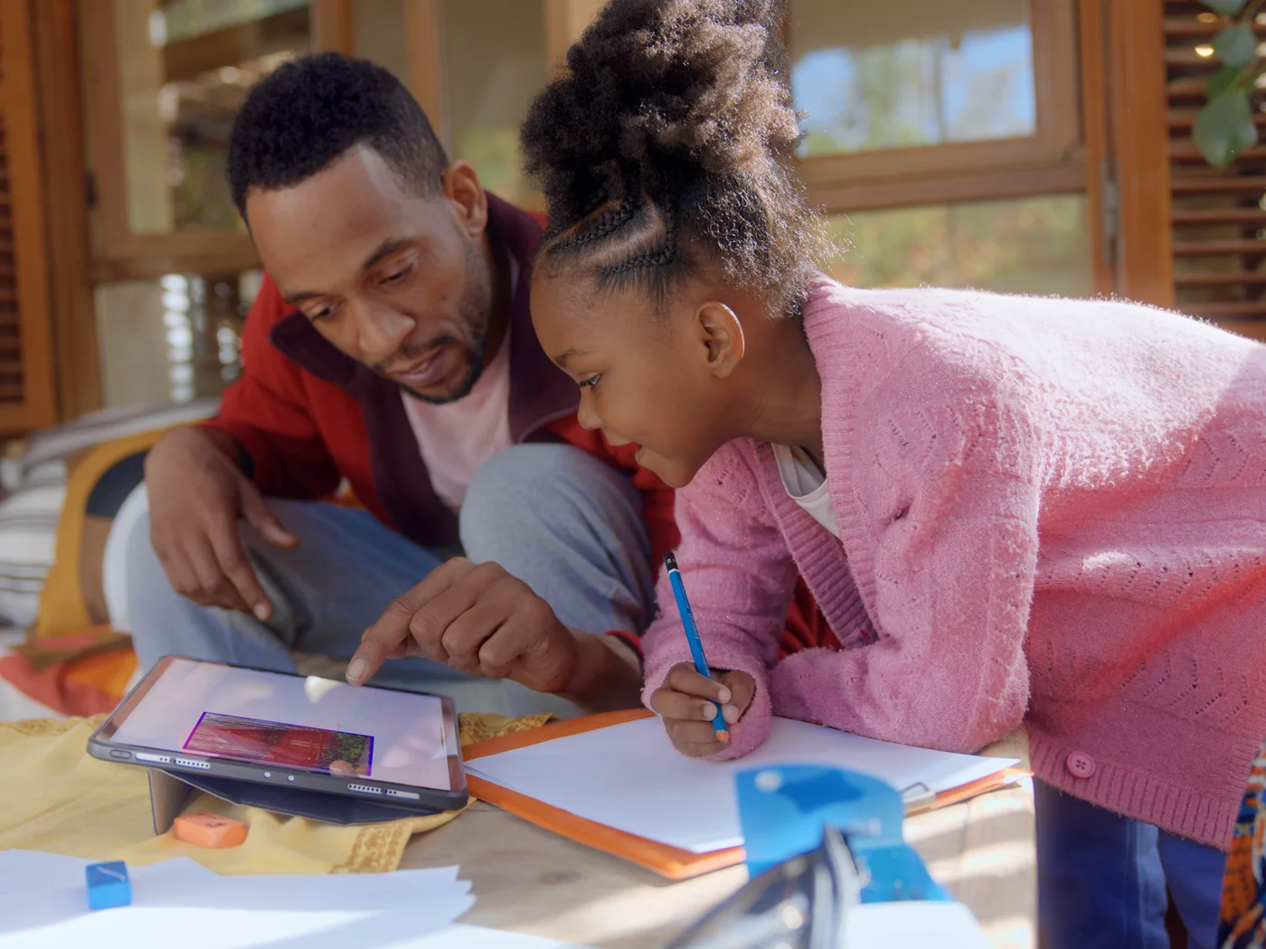 A father and daughter following a drawing lesson on an iPad together