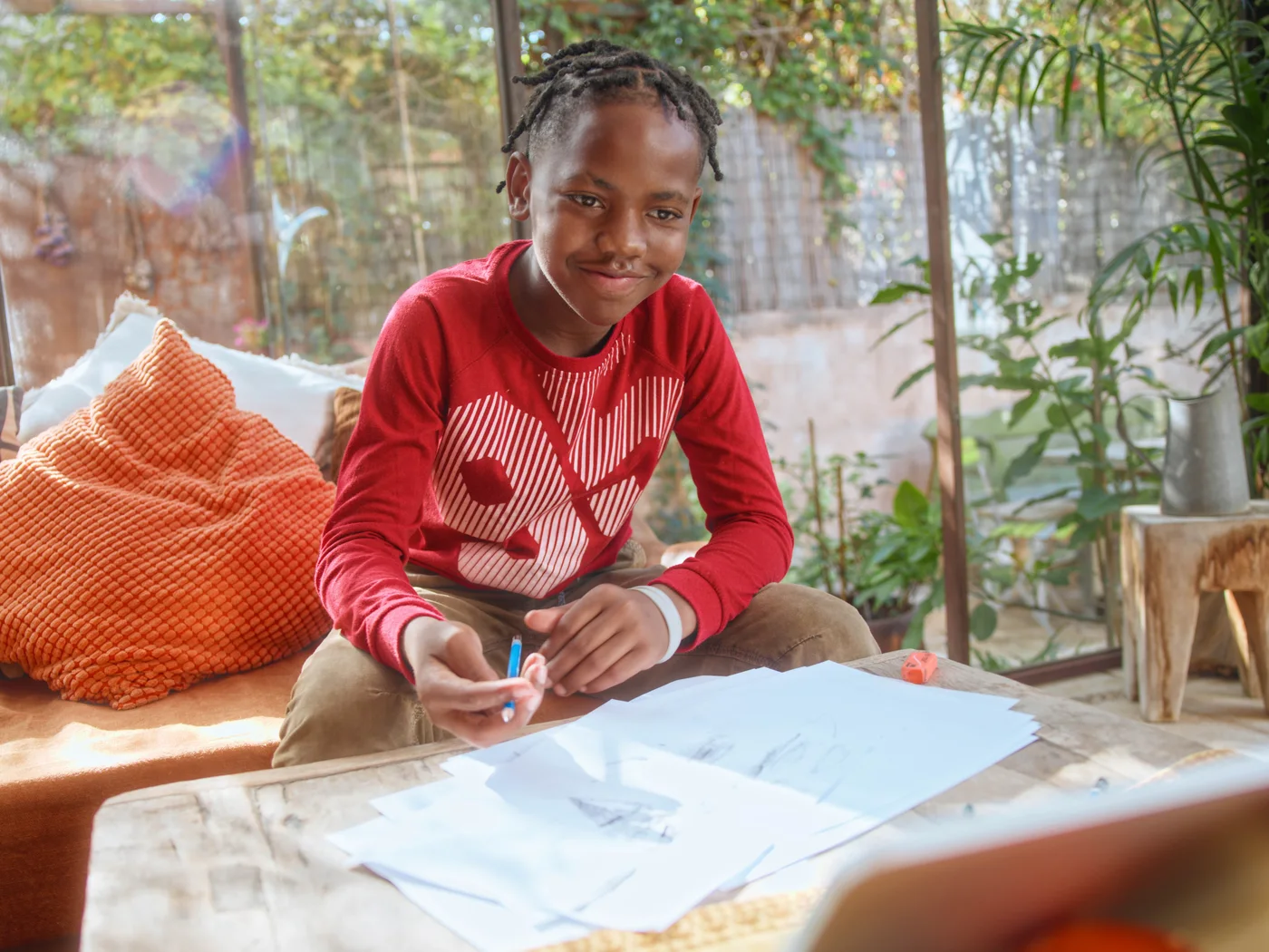 A smiling boy at a table covered with his pencil sketches